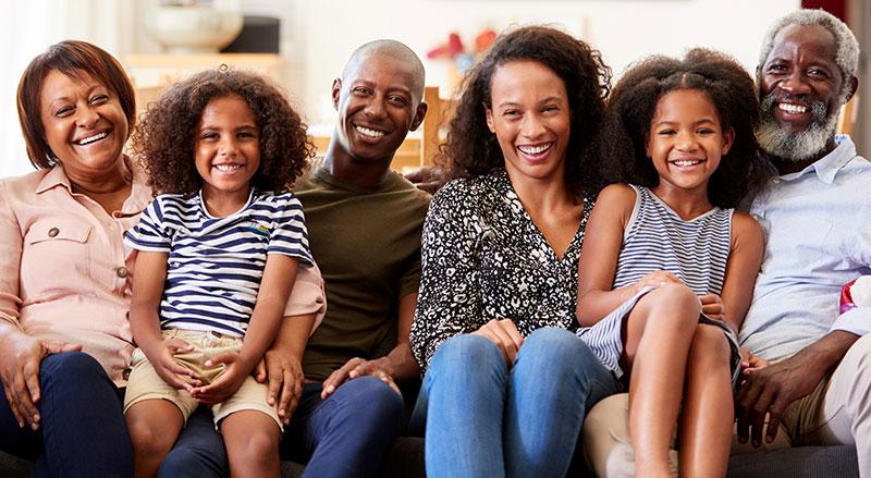 Multigenerational African American family sits together on a couch