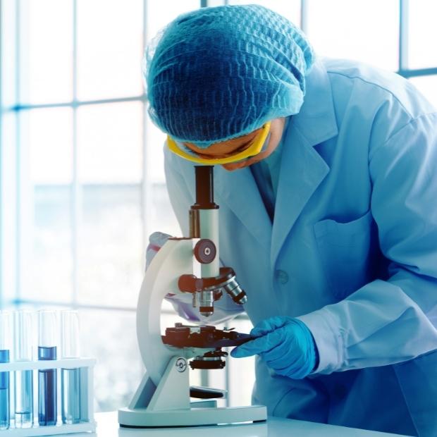 Researcher in lab looking through microscope
