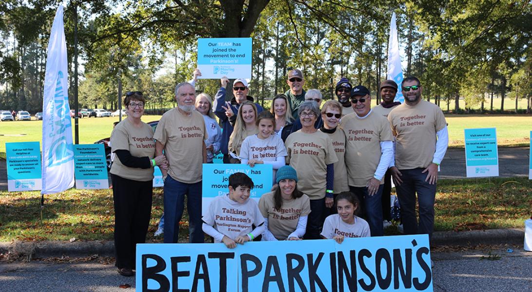 Moving Day team in front of a big sign that says Beat Parkinson's