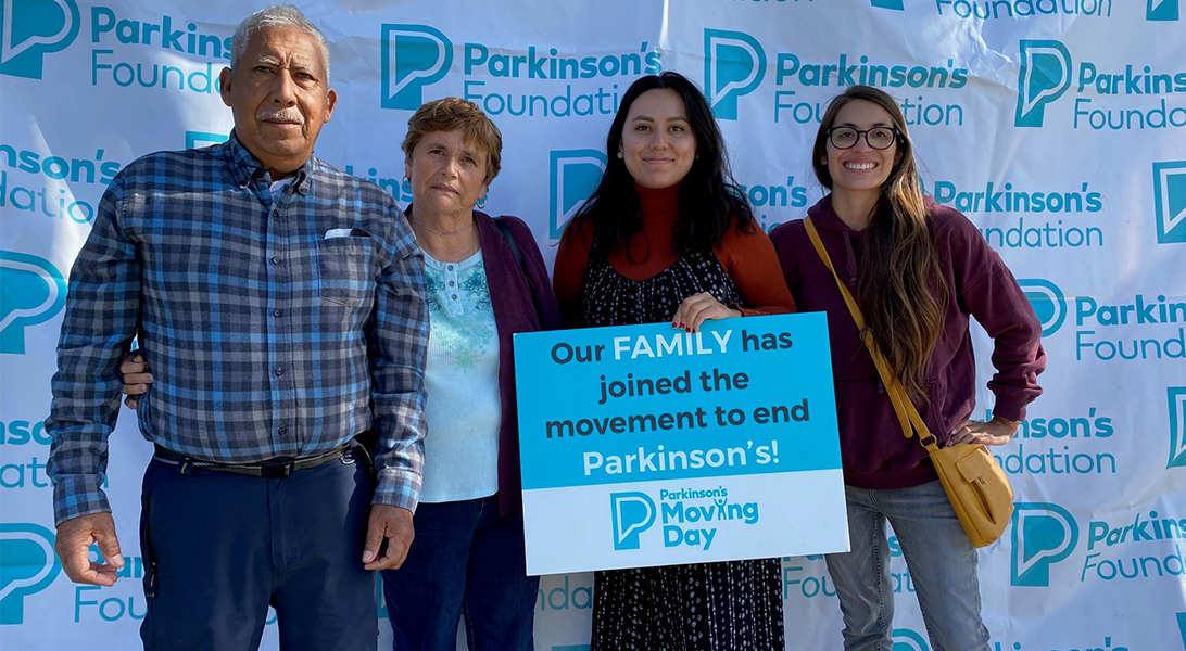 Family stands in front of Parkinson's Foundation logo with sign reading Our Family has joined the movement to end Parkinson's