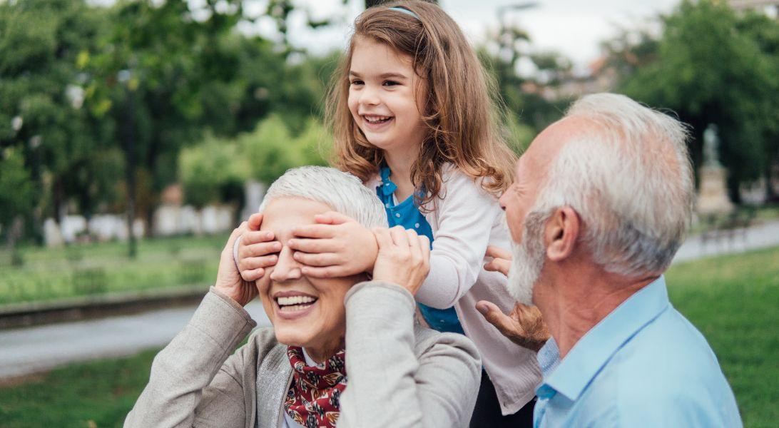 Granddaughter covering grandmas eyes and grandpa laughing