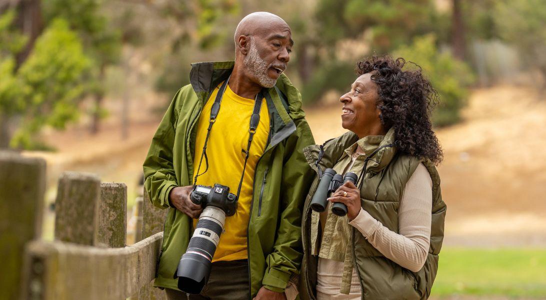 Couple outside carrying a camera and binoculars