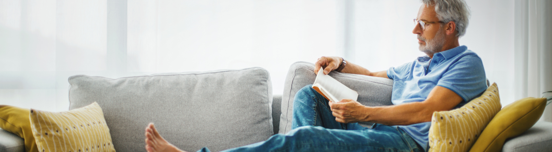 Man sitting on couch reading book