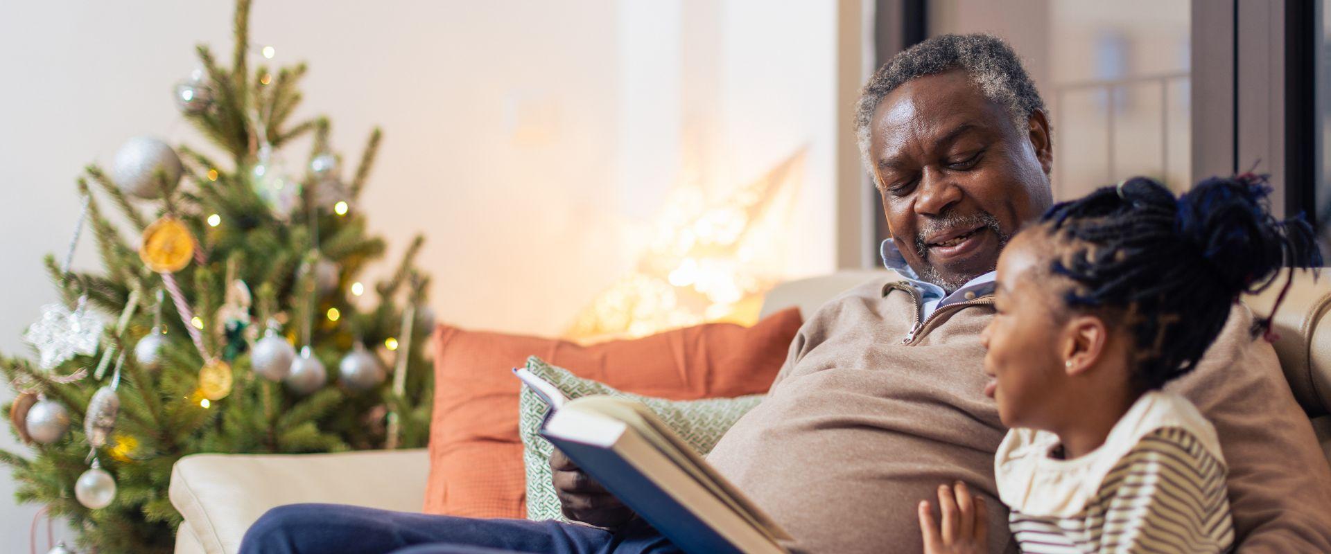 Grandpa and granddaughter sitting on the couch reading a book