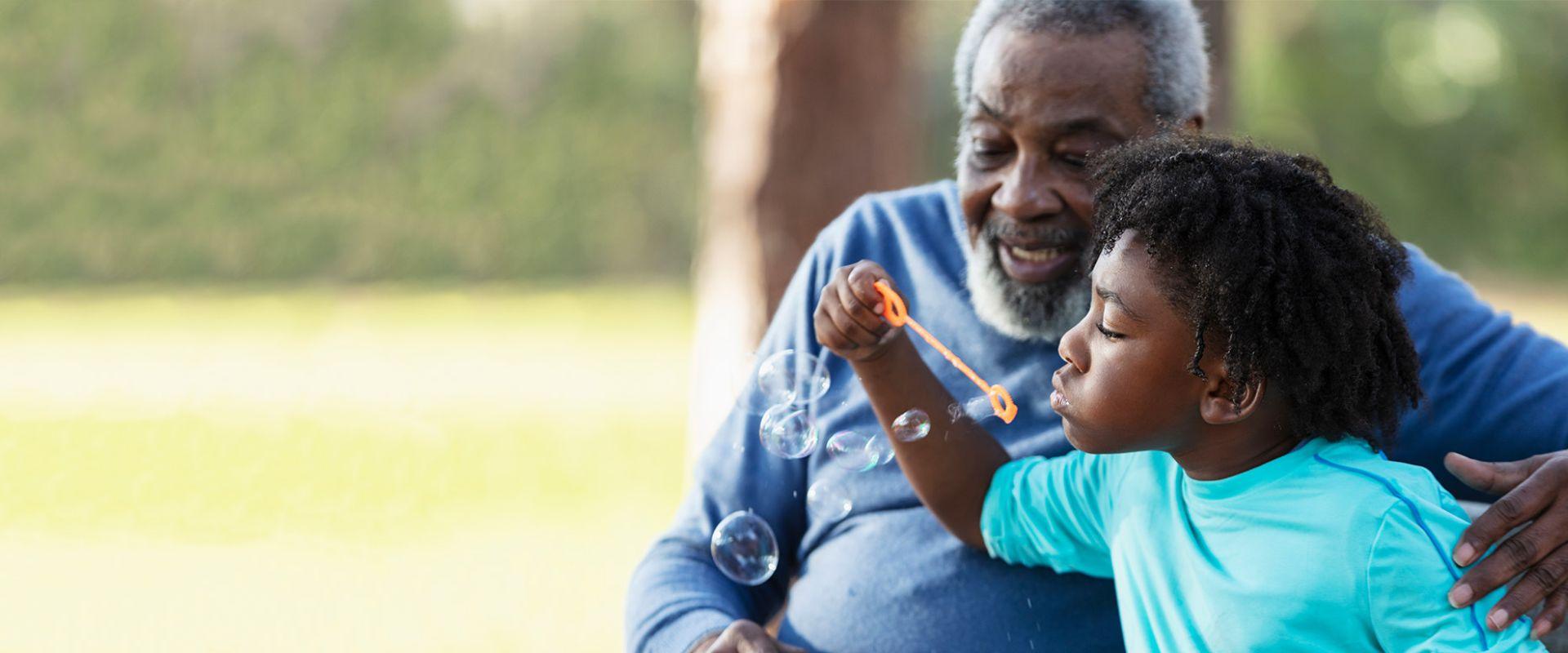 Boy blowing bubbles with grandfather