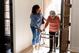 Caregiver assisting an elderly woman with a walker