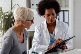 Female doctor and female patient sitting together looking at paperwork