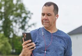 Man on a walk looking at his phone with headphones on