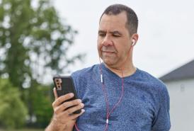 Man on a walk looking at his phone with headphones on