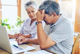 Husband frustrated while looking at laptop and wife comforting him