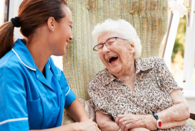 Older woman laughing with a nurse