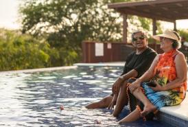 pareja sentada al borde de la piscina en un resort