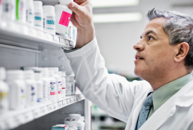 Pharmacist organizing pill bottles on a pharmacy shelf