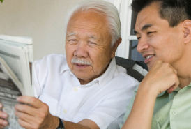 Grandfather and son reading a newspaper together