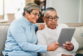 Hispanic couple on their couch looking at a tablet
