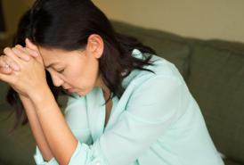 Woman with her head in her hands while experiencing dizziness