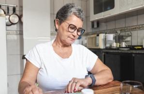 Woman looking at watch while adding pills to scheduler