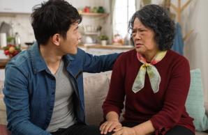 Mother with pained expression sitting on couch with her son