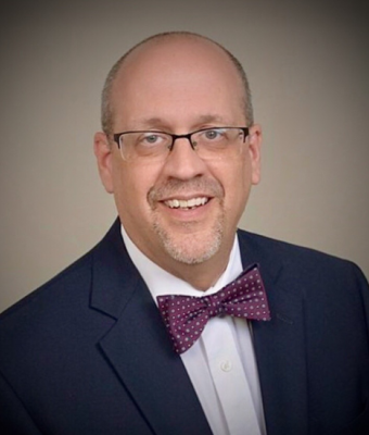 Man in a suit smiling at the camera.
