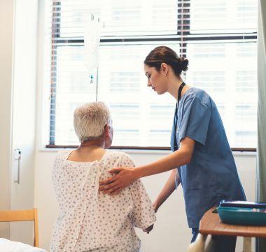 Nurse assisting patient out of hospital bed