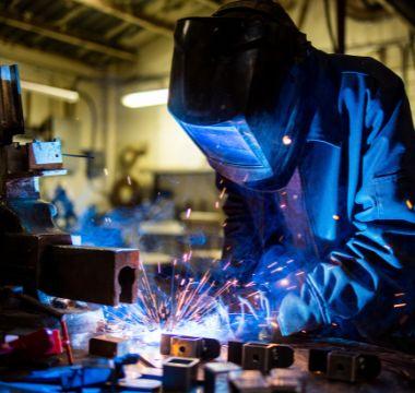 Welder wearing full gear and welding something