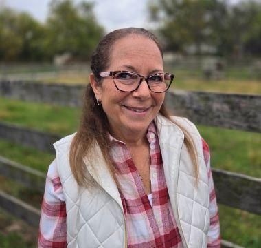 Deb Baittie smiling by a fence