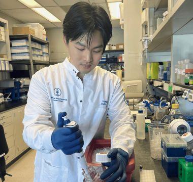 Donghe Yang working with a pipette in a laboratory.