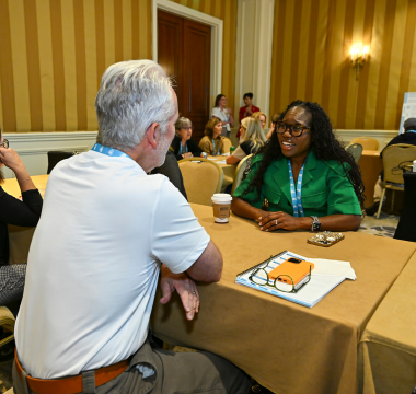 People chatting at a desk at a past Volunteer Summit