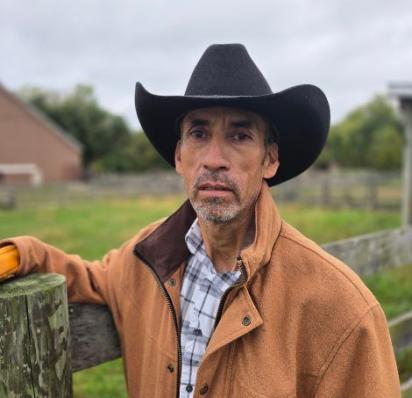 Fidel Guzman standing against a fence