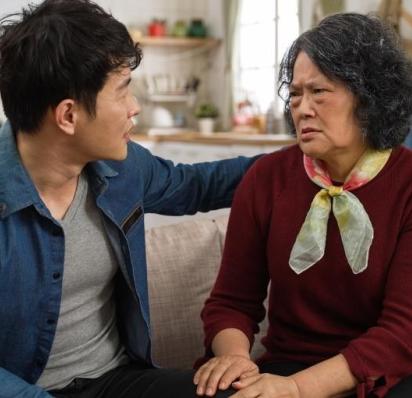 Mother with pained expression sitting on couch with her son