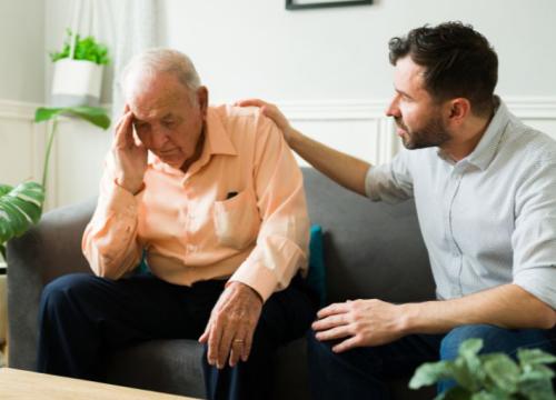 Man holding his head in pain and grandson comforting him