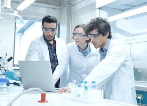 Group of three researchers in a lab looking at a laptop