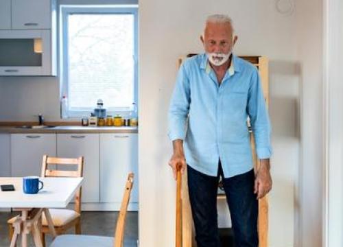 Man using cane standing still in dinning room