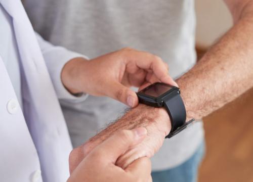 Doctor looking at a patient's movement-tracking device on his wrist