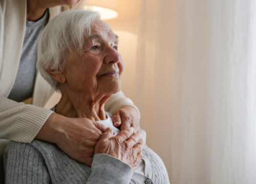 an elderly mother looking off in the distance while being hugged by her daughter not in the frame