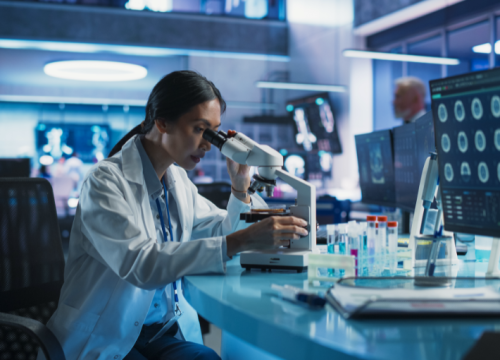 female scientist viewing a slide under a microscope in lab setting