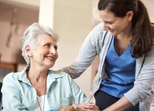 Nurse standing next to a lady in a wheelchair at nursing home