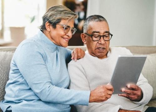 Hispanic couple on their couch looking at a tablet
