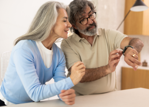 A man and woman checking the man's smart watch.