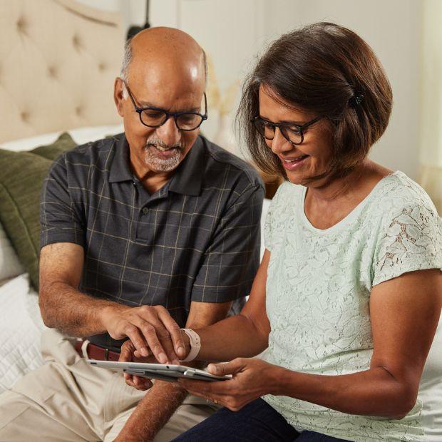 Couple sitting on the bed looking at a tablet