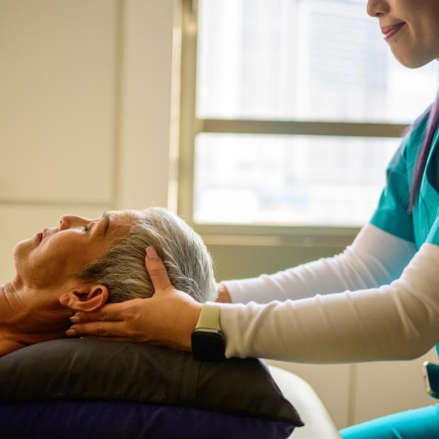 Nurse providing neck stability to older patient lying down
