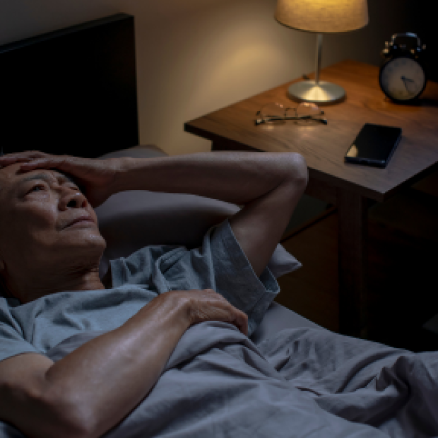 Man laying in bed having trouble sleeping