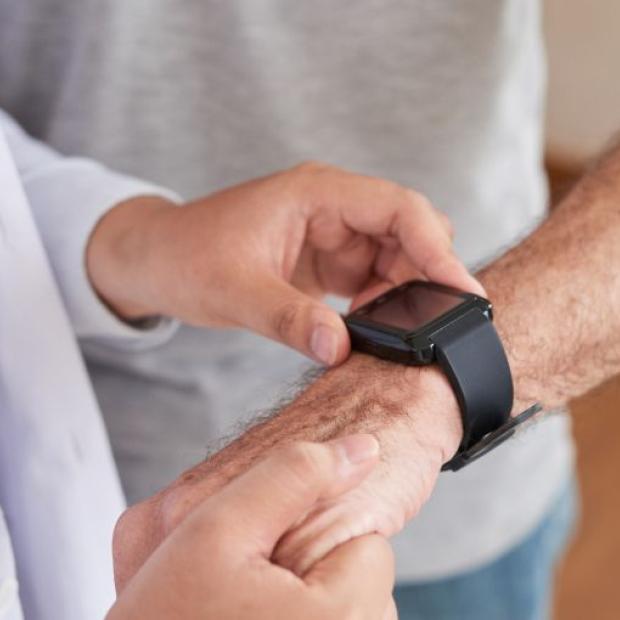 Doctor looking at a patient's movement-tracking device on his wrist