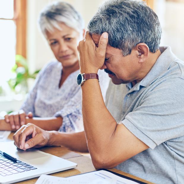 Husband frustrated while looking at laptop and wife comforting him