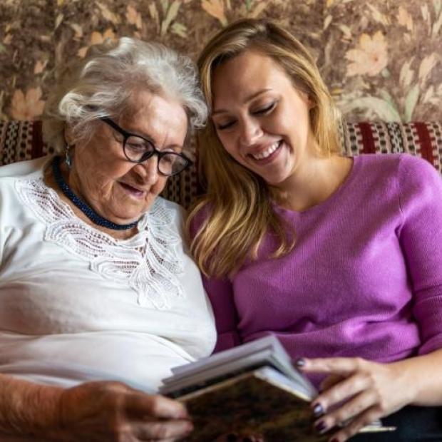 Woman and adult daughter sitting on couch with book