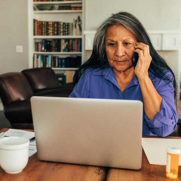 Older woman on the phone while looking at her computer