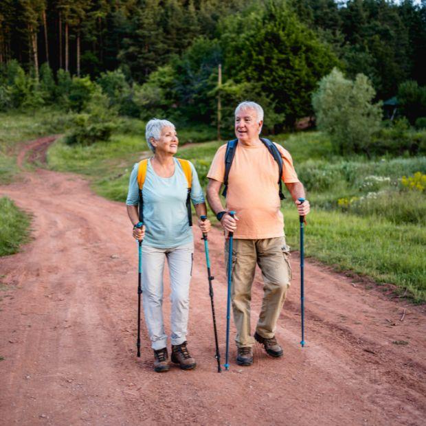 Senior couple walking with trekking poles on a trail