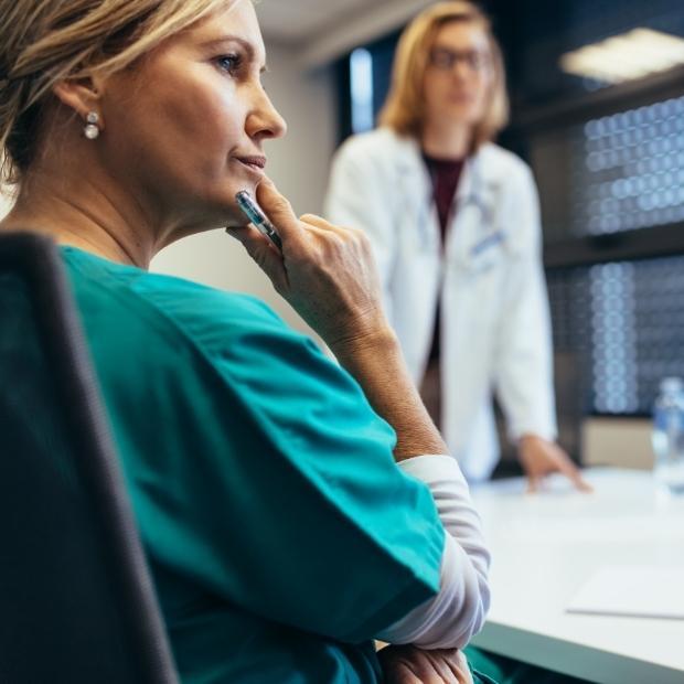 Nurse in a meeting looking at doctor speaking