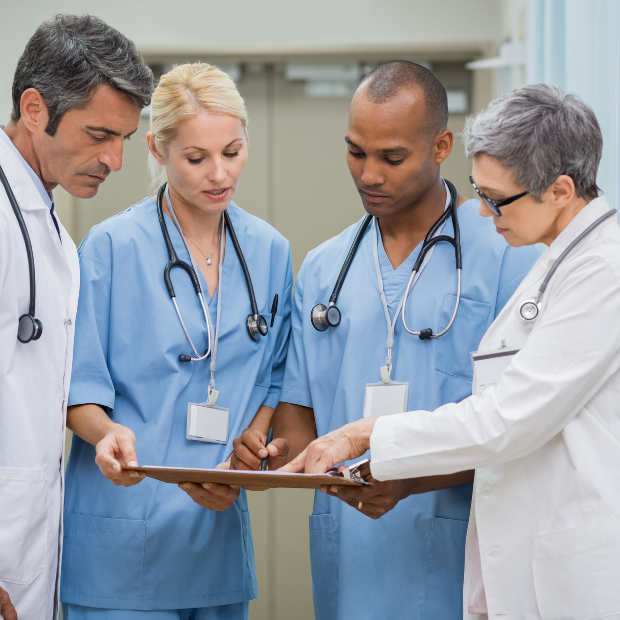 Group of 4 doctors and nurses looking at a clipboard