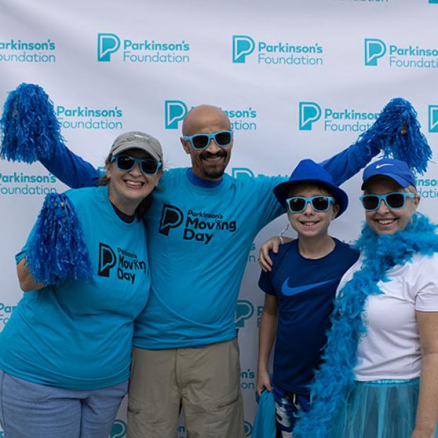 Family posing at Moving Day with blue pom poms